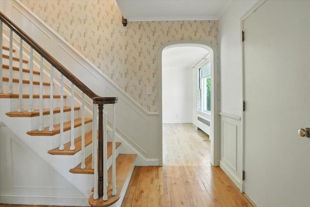 49 Bardwell St, Lewiston, ME 04240 - staircase featuring wallpapered walls, hardwood / wood-style floors, radiator, crown molding, and a wainscoted wall