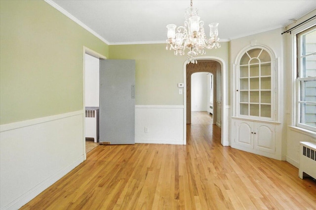 49 Bardwell St, Lewiston, ME 04240 - unfurnished dining area with arched walkways, light wood-style floors, crown molding, a chandelier, and wainscoting