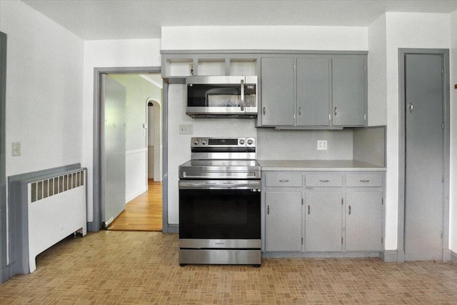 49 Bardwell St, Lewiston, ME 04240 - kitchen featuring stainless steel appliances, gray cabinets, light countertops, radiator, and arched walkways