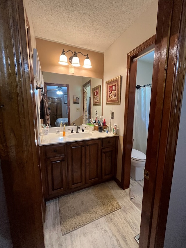 bathroom with hardwood / wood-style flooring, vanity, a textured ceiling, and toilet