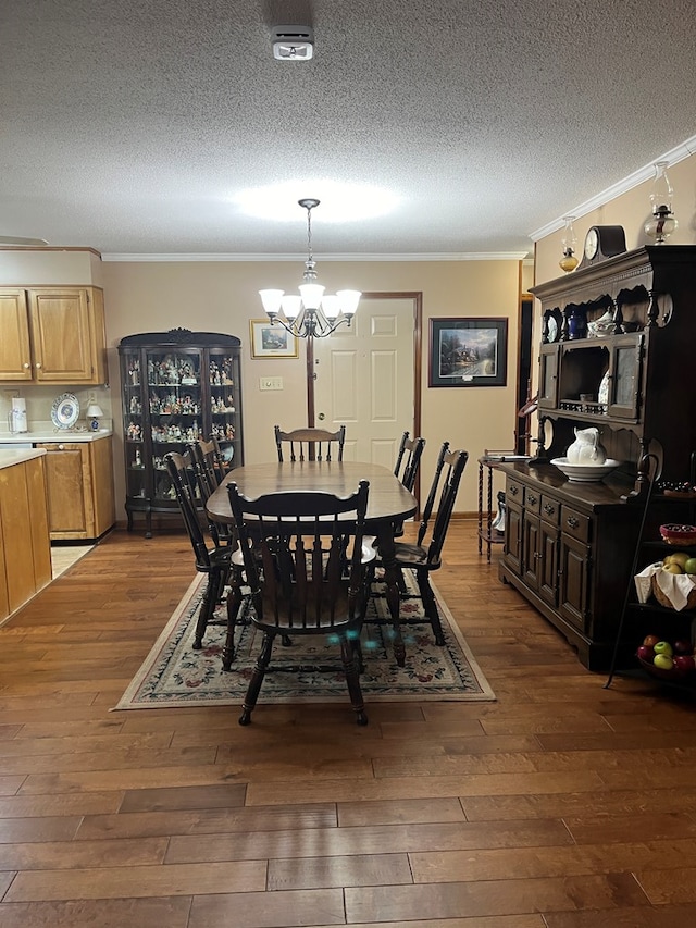 dining room with crown molding, a chandelier, dark wood-type flooring, and a textured ceiling