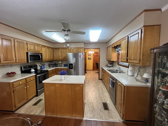 kitchen featuring a kitchen island, appliances with stainless steel finishes, sink, crown molding, and light wood-type flooring