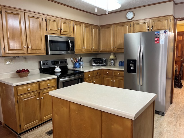 kitchen with ornamental molding, stainless steel appliances, a textured ceiling, and a kitchen island