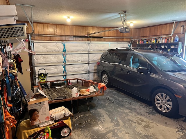 garage featuring a garage door opener and wooden walls