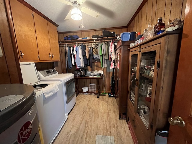 laundry area with crown molding, washing machine and dryer, cabinets, light hardwood / wood-style floors, and wood walls