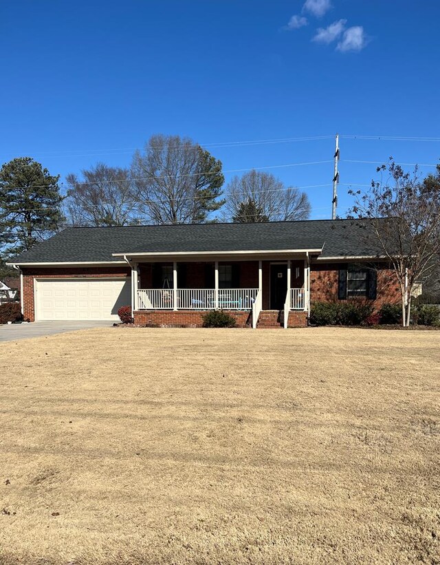 ranch-style home featuring a garage, covered porch, and a front lawn