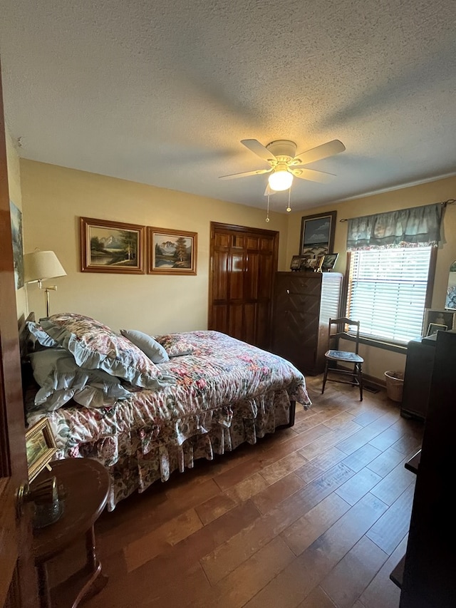 bedroom featuring ceiling fan, dark hardwood / wood-style flooring, and a textured ceiling