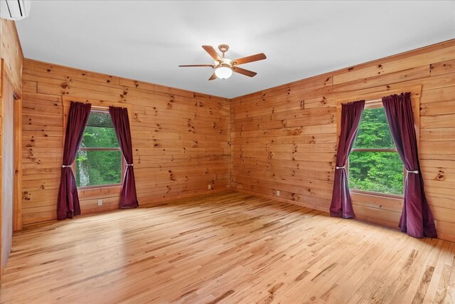 3691 Flagpole Rd, Ellijay, GA 30540 - spare room with light wood-style floors, wooden walls, ceiling fan, an AC wall unit, and healthy amount of natural light