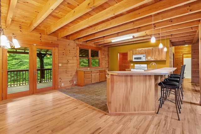 3691 Flagpole Rd, Ellijay, GA 30540 - kitchen with white microwave, range, light wood-style flooring, wood walls, and light countertops