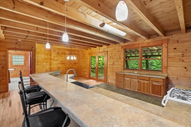 3691 Flagpole Rd, Ellijay, GA 30540 - kitchen featuring wooden walls, a sink, wood ceiling with exposed beams, decorative light fixtures, and light countertops
