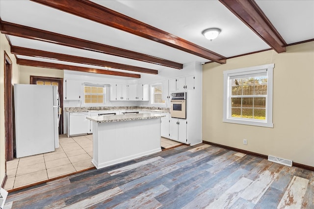 kitchen featuring white appliances, visible vents, white cabinets, and a wealth of natural light