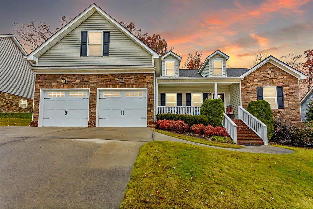 view of front of property featuring a porch, a garage, and a yard