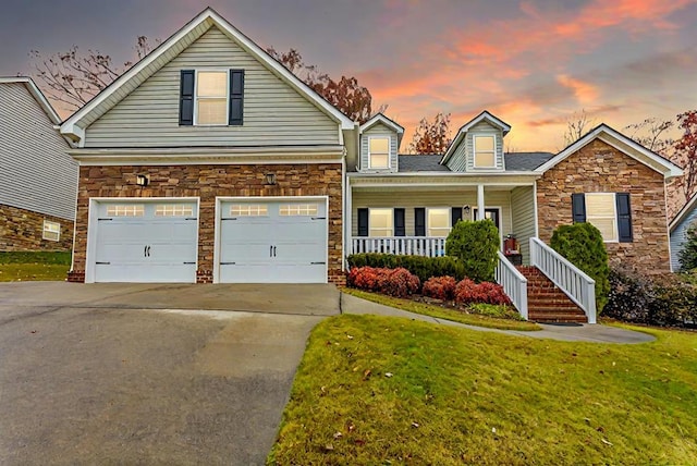 view of front of property featuring a porch, a garage, and a yard