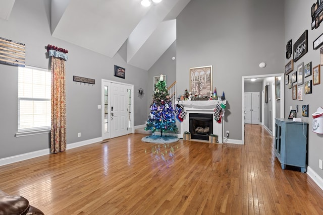 foyer featuring high vaulted ceiling, hardwood / wood-style floors, a fireplace, and baseboards