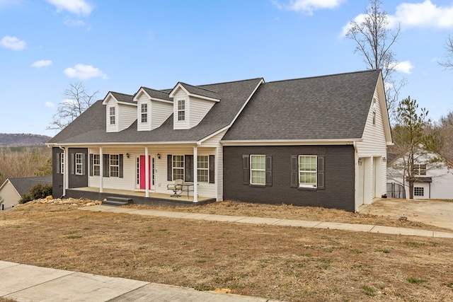 cape cod house with a garage, a shingled roof, concrete driveway, covered porch, and brick siding