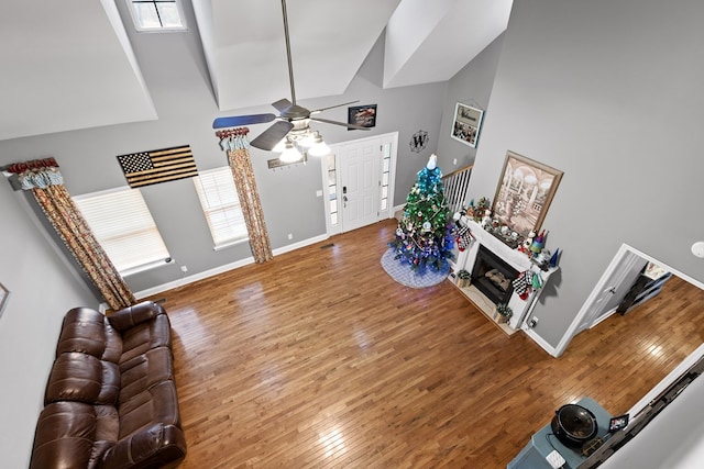 foyer with a ceiling fan, a fireplace, baseboards, and hardwood / wood-style floors