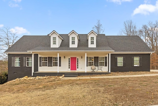 cape cod home with a porch, brick siding, crawl space, roof with shingles, and a front lawn