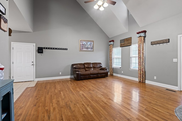 unfurnished room featuring baseboards, visible vents, ceiling fan, light wood-type flooring, and high vaulted ceiling