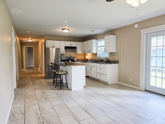 106 Santa Fe Trl NW, Dalton, GA 30721 - kitchen featuring stainless steel appliances, range hood, a center island, white cabinetry, and a kitchen breakfast bar