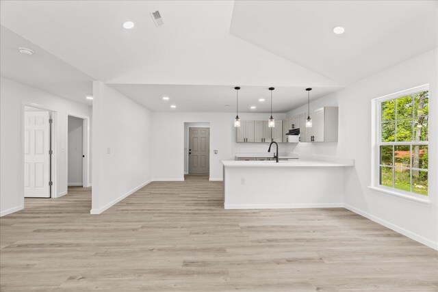kitchen featuring light countertops, a sink, a peninsula, lofted ceiling, and recessed lighting