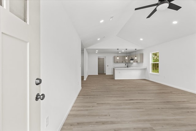 unfurnished living room with ceiling fan, a sink, light wood finished floors, recessed lighting, and lofted ceiling