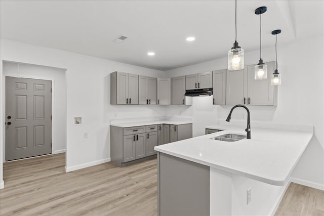 kitchen with exhaust hood, a sink, gray cabinets, a peninsula, and baseboards