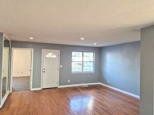 foyer entrance with dark hardwood / wood-style floors and a textured ceiling