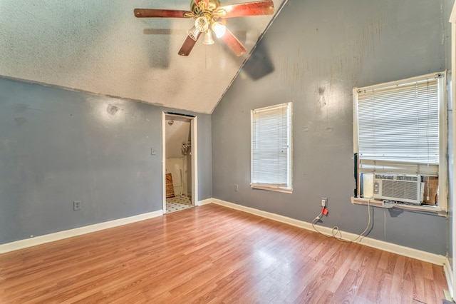 empty room featuring baseboards, vaulted ceiling, cooling unit, wood finished floors, and a ceiling fan