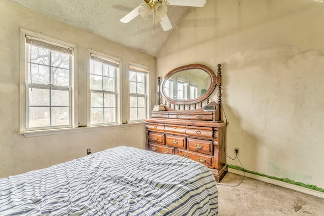 bedroom featuring a textured ceiling, vaulted ceiling, multiple windows, and ceiling fan