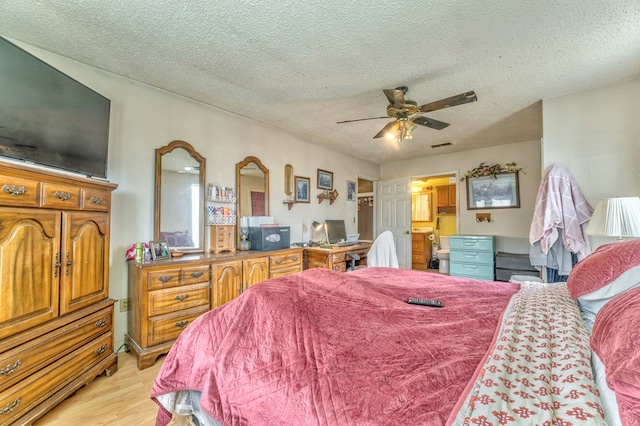 bedroom featuring light wood-type flooring, visible vents, a textured ceiling, ensuite bath, and ceiling fan