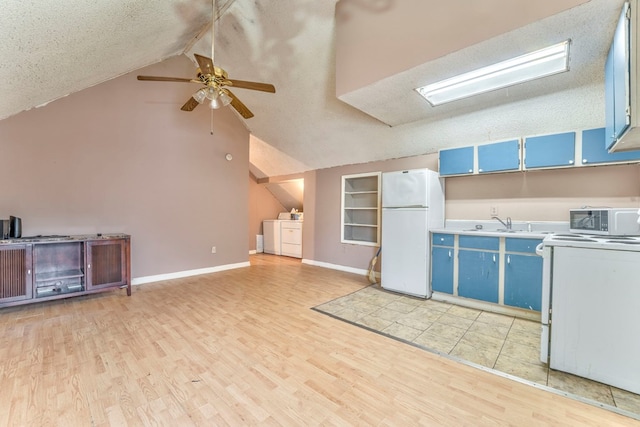 kitchen with blue cabinets, white appliances, vaulted ceiling, and washer and clothes dryer