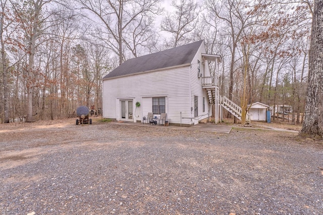 view of home's exterior with driveway, an outbuilding, and stairs