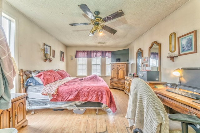 bedroom with ceiling fan, wood finished floors, visible vents, and a textured ceiling