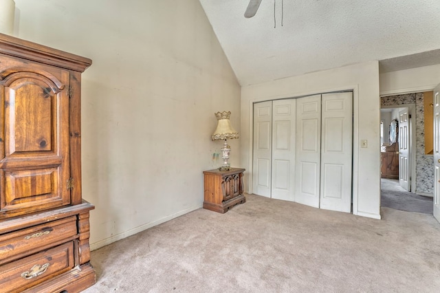 carpeted bedroom featuring a textured ceiling, a closet, baseboards, lofted ceiling, and ceiling fan