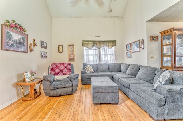 living area with high vaulted ceiling, light wood-type flooring, and baseboards