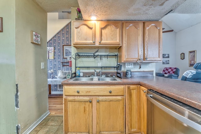 kitchen featuring a sink, stainless steel dishwasher, a textured ceiling, light tile patterned flooring, and baseboards