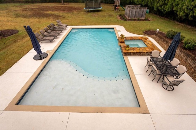 pool featuring a lawn, a patio area, a trampoline, and an in ground hot tub