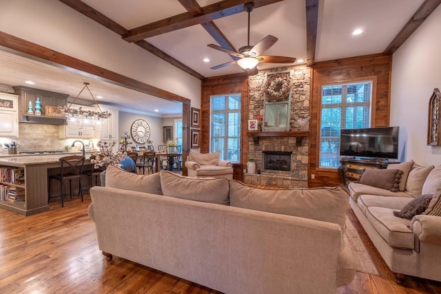 living room featuring recessed lighting, wood-type flooring, beam ceiling, a ceiling fan, and a fireplace