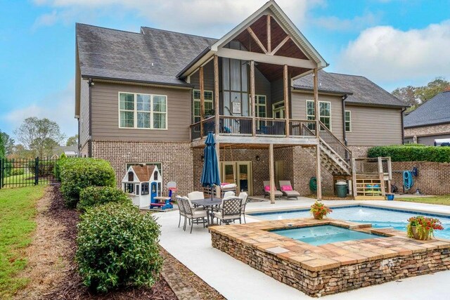 rear view of property with a pool with hot tub and a patio area