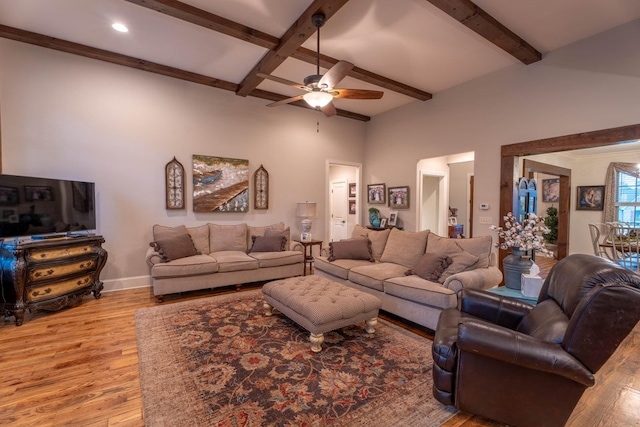 living room with beamed ceiling, ceiling fan, and light wood-type flooring