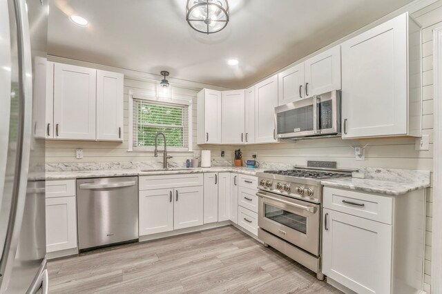 3012 Brookhaven Cir, Dalton, GA 30720 - kitchen featuring white cabinets, light stone countertops, appliances with stainless steel finishes, a sink, and light wood finished floors