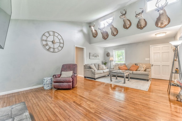 living area featuring baseboards, high vaulted ceiling, and hardwood / wood-style flooring