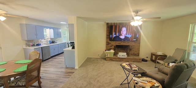 living room with a brick fireplace, sink, hardwood / wood-style floors, and ceiling fan