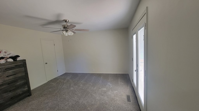 unfurnished bedroom with ceiling fan and dark colored carpet