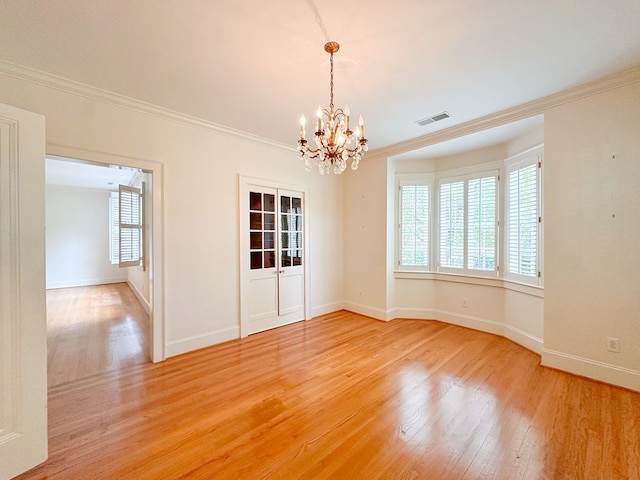 unfurnished room with hardwood / wood-style flooring, ornamental molding, and a chandelier