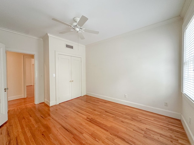 unfurnished bedroom with crown molding, ceiling fan, light wood-type flooring, and a closet