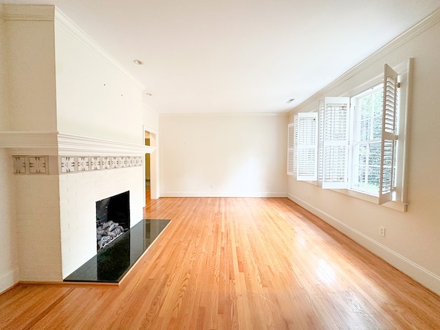 unfurnished living room with crown molding, a brick fireplace, and wood-type flooring