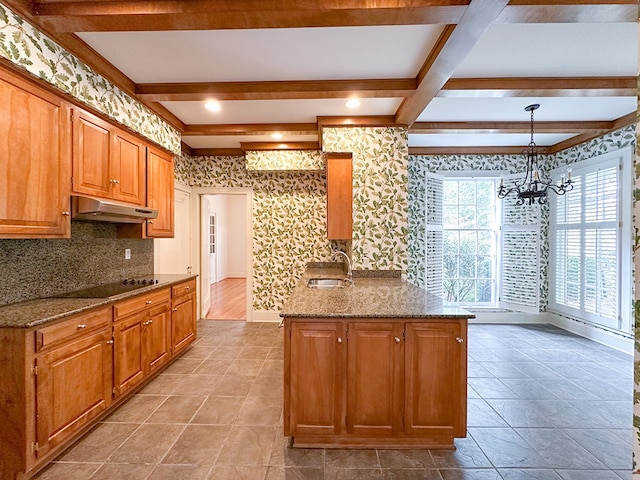 kitchen with black electric cooktop, dark stone counters, sink, and hanging light fixtures