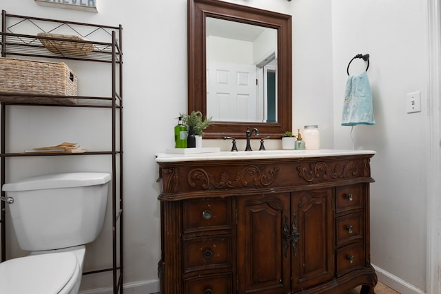 bathroom featuring baseboards, vanity, and toilet