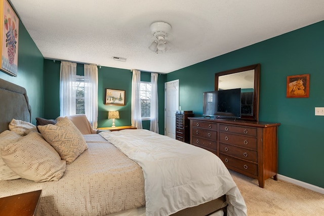 bedroom featuring baseboards, a textured ceiling, visible vents, and light colored carpet